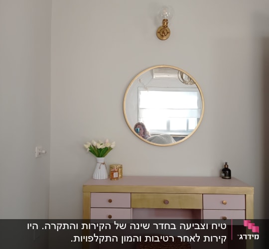 שולחן ורוד עם מראה עגולה על הקיר